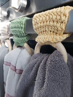 several towels hanging from the handle of an oven with rings attached to them, all in different colors