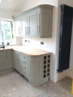 a kitchen with grey cabinets and wooden counter tops in the middle of the floor, next to a radiator