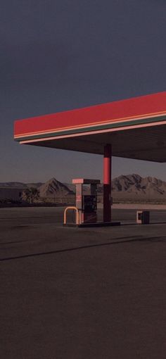 an empty gas station in the middle of nowhere, with mountains in the back ground