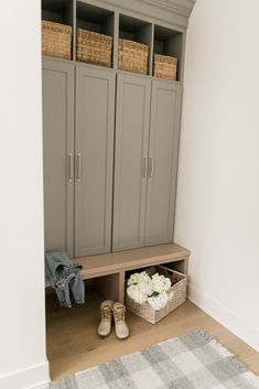 an entryway with gray cupboards and white flowers in baskets on the floor next to it