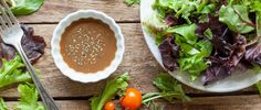 a wooden table topped with salad and dressing