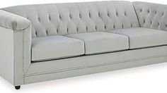 a light gray couch with buttons on the back and arm rests against a white background