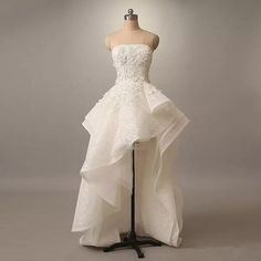 a white wedding dress on a mannequin in front of a gray background,