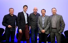 five men standing in front of a projection screen