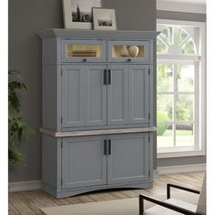 a gray cabinet with two doors and drawers in a living room next to a window