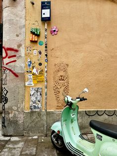 a green scooter parked next to a building with graffiti on it's walls