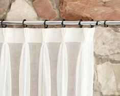 a white curtain hanging on the side of a stone wall