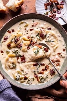 a bowl filled with chicken and dumpling soup on top of a wooden table next to bread