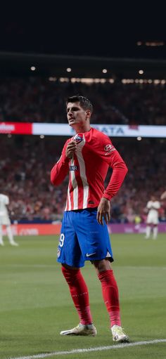 a soccer player is standing on the field with his hand in his mouth and holding a ball