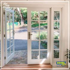 an open white door leading to a driveway with trees in the back ground and bushes on either side