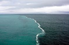 an aerial view of the ocean with waves coming in to shore and clouds above it