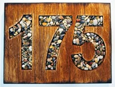 a wooden sign with rocks in the shape of number seventy five on it's side