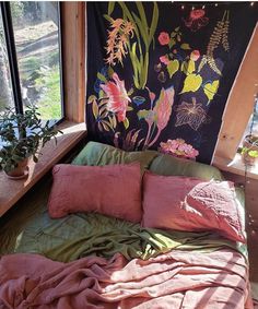 a bed covered in pink sheets and pillows next to a window