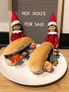 two elfs are eating hot dogs for sale on a plate next to a sign that says hot dogs for sale