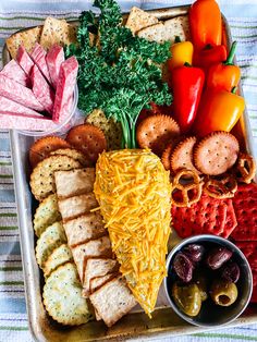 a platter with cheese, crackers, vegetables and meats is shown here