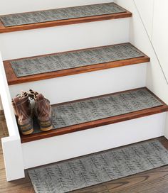 two pairs of shoes are sitting on the steps in front of a set of carpeted stairs