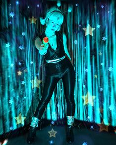 a woman in black leather pants holding a red rose with stars on the wall behind her