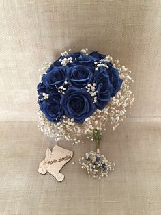 a bouquet of blue roses and baby's breath sits next to a small brooch