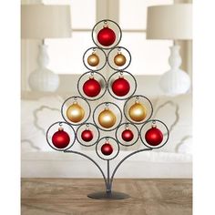 a metal christmas tree with red and gold baubles on it's base