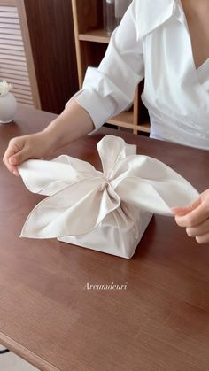 a woman sitting at a table with a napkin wrapped in a bow on top of it