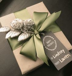 a present wrapped in brown paper with a green bow and pine cones on it's side