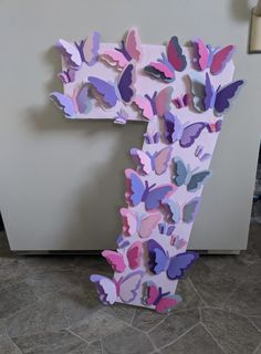 the letter f is made out of paper and has many butterflies on it's side