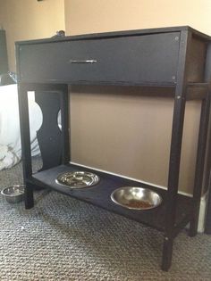 a black cabinet with two bowls on it in the middle of a carpeted room