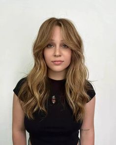 Discover how gentle waves in a honey-blonde hue can give a relaxed, elegant vibe, especially with long, delicate bangs framing the eyes. Ideal for round faces, this style adds a whisper of grace. Click to see our gallery and follow us on Pinterest for more inspirations! ** Photo Credit: Instagram @chrismcmillanthesalon