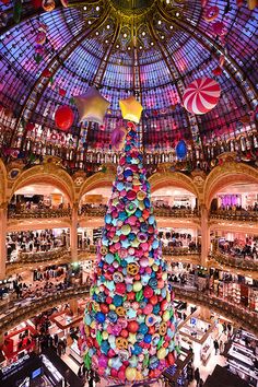 a large christmas tree in the middle of a shopping mall with lots of balloons hanging from it's ceiling