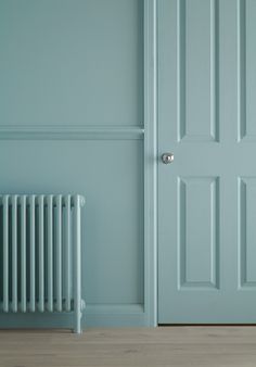 an empty room with a blue door and radiator next to the wall in front of it