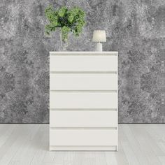 a white dresser sitting in front of a wall with a potted plant on top