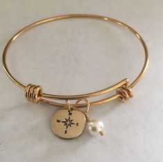 "This listing includes a gold plated stainless steel expandable bangle bracelet with a 1/2\" nu gold discs hand stamped with a compass paired with a Swarovski white pearl. Nu-gold is a copper alloy consisting of 85% copper and 15% zinc. It has a rich warm color and if highly polished resembles gold. This is also known as jewelers brass and will tarnish and need to be polished. What I would like you to know: All of my pieces are hand stamped and made with love just for you. They will arrive in a Gold Stainless Steel Jewelry For Wedding, Gold Stainless Steel Bangle Charm Bracelet, Matte Gold Adjustable Bangle Jewelry, Matte Gold Bangle Jewelry For Gift, Stainless Steel Bangle For Wedding, Gold-colored Stainless Steel Wedding Bracelet, Gold Charm Bracelet With Extender For Friendship, Adjustable Gold-tone Charm Bracelet Gift, Adjustable Gold Charm Bracelet For Wedding