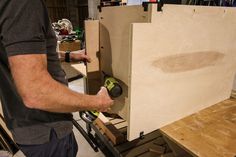 a man working on a piece of wood with a power drill in his right hand