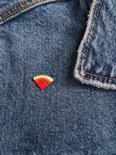 a watermelon pin sitting on the back of a jean jacket's pocket