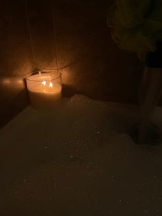 a lit candle sitting on top of a bath tub next to a vase filled with flowers