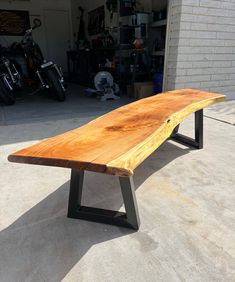 a wooden bench sitting on top of a cement floor next to a motorcycle garage door