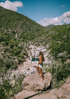 a woman standing on top of a large rock