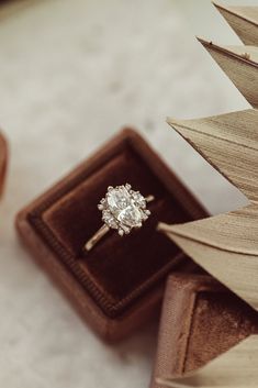 an engagement ring sitting in a wooden box next to a tree ornament on top of a table