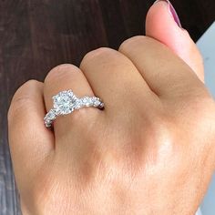 a woman's hand holding an engagement ring with two diamonds on top of it