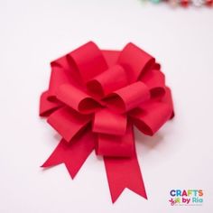 a close up of a red bow on a white surface with beads in the background