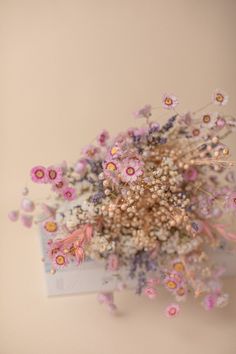 a bunch of flowers that are on top of a table in front of a wall