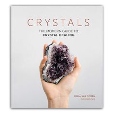 a hand holding a rock with the title crystals, the modern guide to crystal - healing