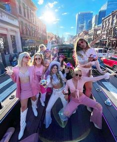 several women in pink outfits posing on the back of a truck