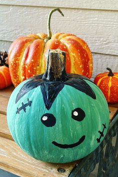 painted pumpkins with faces on them sitting on a bench