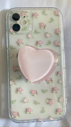 an iphone case with a pink heart shaped object in the middle and flowers on it