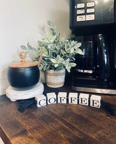 a potted plant sitting on top of a wooden table next to blocks spelling coffee