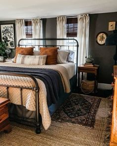 a bed sitting in a bedroom next to a window with curtains on the windowsill