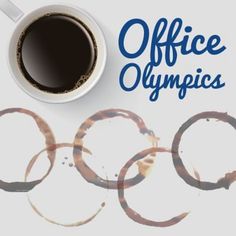 a cup of coffee sitting on top of a white table next to rings and the words office olympics