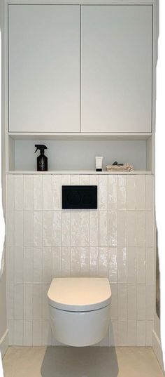 a white toilet sitting in a bathroom next to a wall mounted cabinet and cupboards