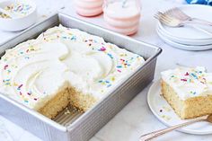 a cake with white frosting and sprinkles in a pan on a table